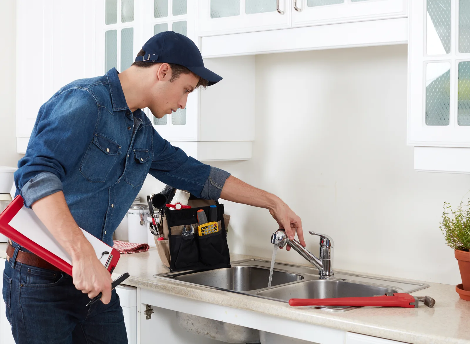 Maintenance technician repairing a kitchen faucet at a Stronger Roots Housing property